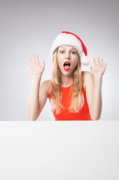 Joyful Beautiful christmas woman in santa hat holding empty board isolated on white background