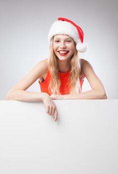 Beautiful christmas woman in santa hat pointing empty board, isolated on white background