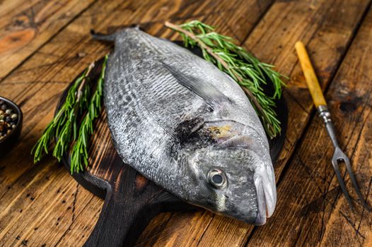 Raw Sea bream or dorado sea fish with spices and herbs on a cutting board. wooden background. Top view.