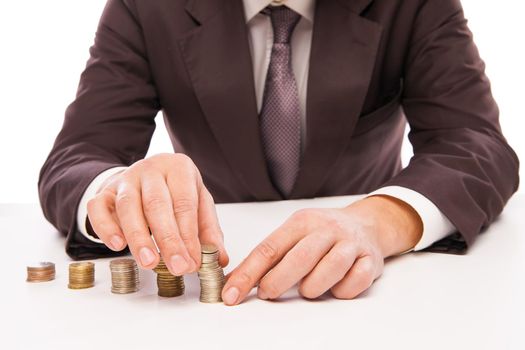 Close-up Of Businessman Placing Coin Over Stack Of Coins At Desk over white backround