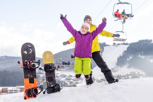 mother and daughter with snowboards in a mountain resort