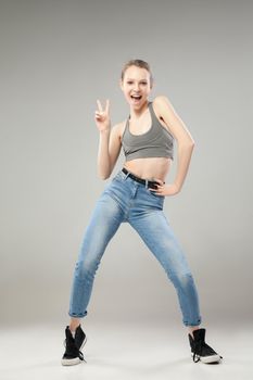 Portrait of young blonde girl showing peace sign and smiling at camera