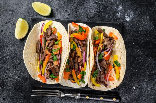 Mexican tacos shells with beef meat, onion, tomato and sweet pepper. Black background. Top view.