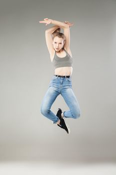 Portrait of blonde young woman jumping in mid air showing pistols with fingers