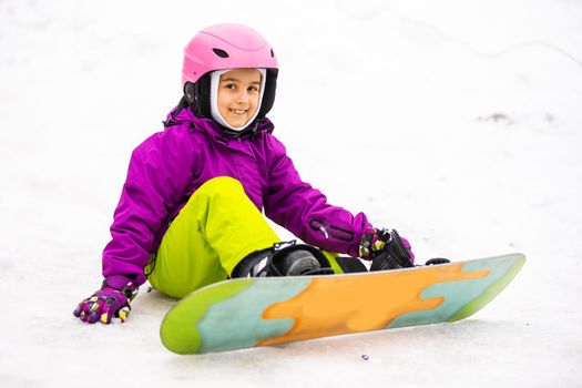 Little Cute Girl Snowboarding at ski resort in sunny winter day.