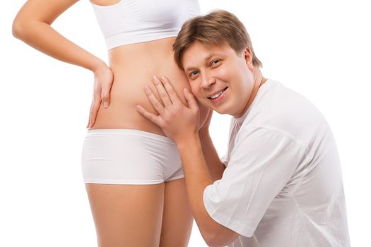 Husband listening to his wife's belly isolated over white