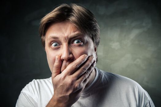 handsome man scared over dark grey background