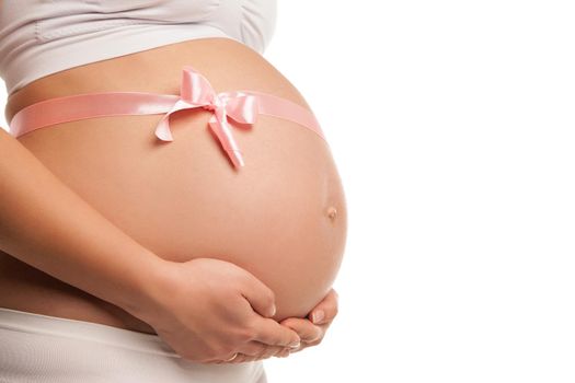 Close up image of pregnant woman tummy with pink ribbon over white