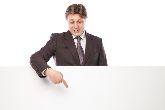Business man holding empty board and pointing to it while smiling to camera on white background