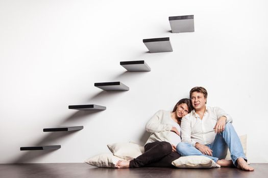 Couple at home sitting on stairs. Pregnant woman