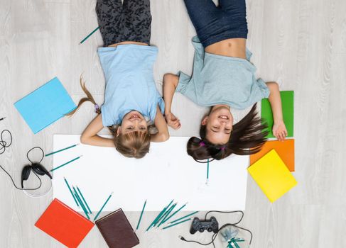 two little girls learn while lying on the floor. Education