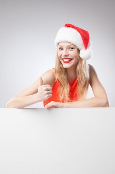 Joyful Beautiful christmas woman in santa hat holding empty board isolated on white background