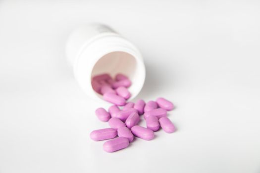 Close-up of bottle of pink tablets scattered on table