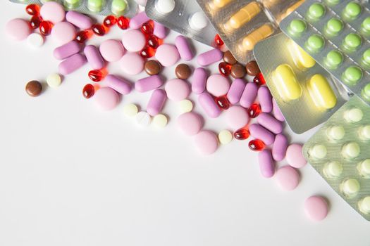 View on scattered pills and tablets in packeges on white background.From above