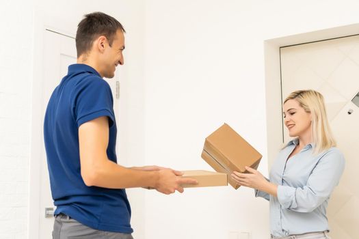 woman receiving boxes from postman at the door in home delivery concept. Woman received the parcel from the postman at home. Postman giving cardboard box to young woman.