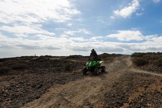 A man riding ATV in sand in protective helmet.