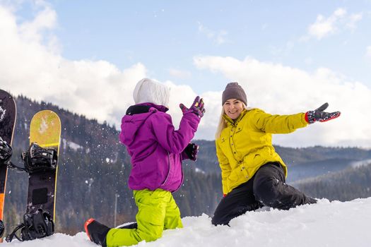 mother and daughter with snowboards at winter resort