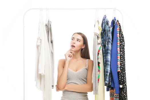 Portrait of thinking brunette woman looking at clothes