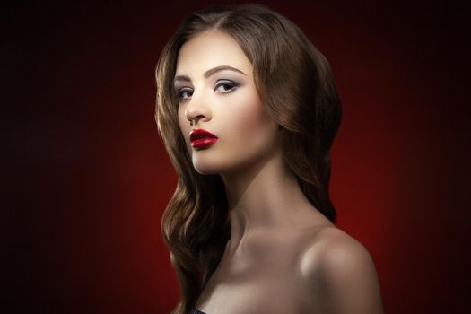 Portrait of beautiful young model with wavy hair and red lips looking at camera