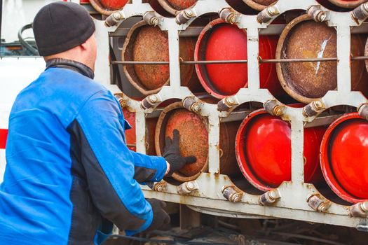 Male industrial worker puts a gas cylinder into a gas machine. Equipment for the safe transportation of propane gas bottles.