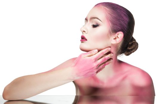 Portrait of young woman with bare shoulders covered with pink glitter