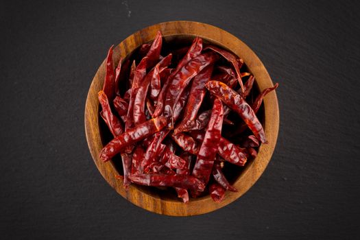 dried chili isolated on black background. In wooden bowl -closeup photo