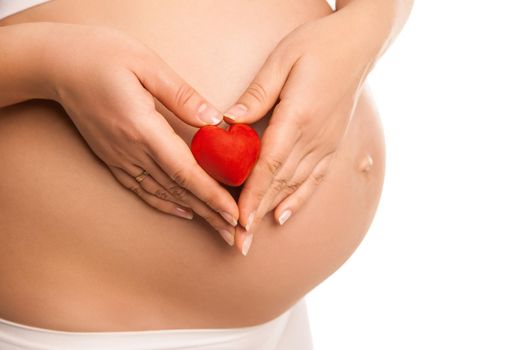 pregnant woman holding in her hands heart symbol over white