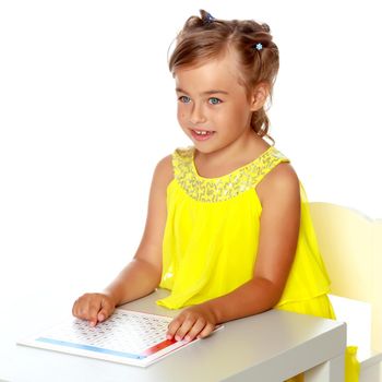 A little girl in Montessori kindergarten sits at a table and studies Montessori stuff. The concept of school and preschool education, harmonious development of the child. Isolated on white background.