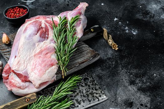 Raw lamb shoulder meat ready for baking with garlic, rosemary. Black background. Top view. Copy space.