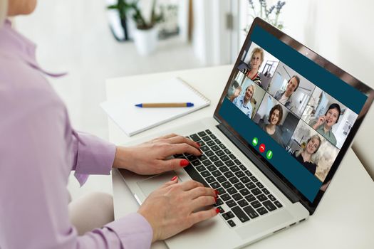 View over businesslady shoulder seated at workplace desk look at computer screen where collage of many diverse people involved at video conference negotiations activity, modern app tech usage concept.