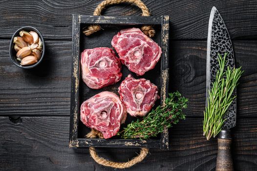 Raw lamb neck meat on a butcher table with knife. Black wooden background. Top view.