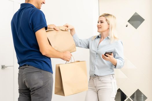 Woman and courier during order transfer. Woman accepting delivery from deliveryman. Cropped image of delivery service worker giving parcel to client.