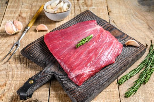 Fresh Raw flank or bavette beef marbled meat steak with rosemary. Wooden background. Top view.