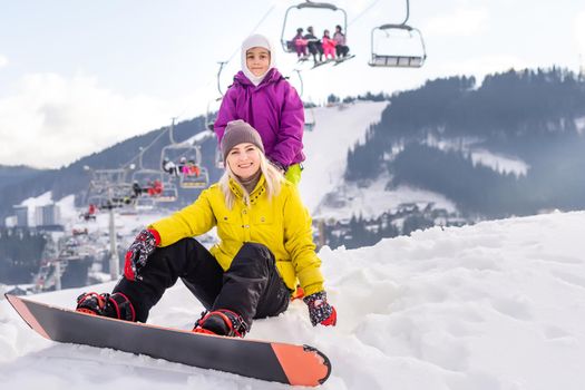 mother and daughter with snowboards at winter resort