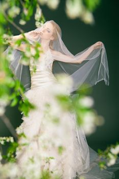 Dreamy beautiful blonde bride walking alone in the park enjoying wind wave and dance