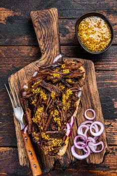 BBQ Texas Sandwich with slow roasted brisket beef meat. Dark wooden background. Top view.