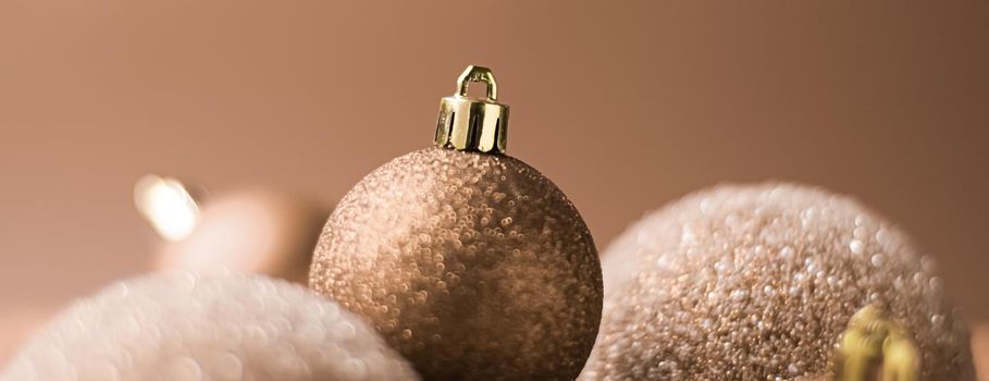 Christmas holiday and festive decoration concept. Golden baubles on beige background.