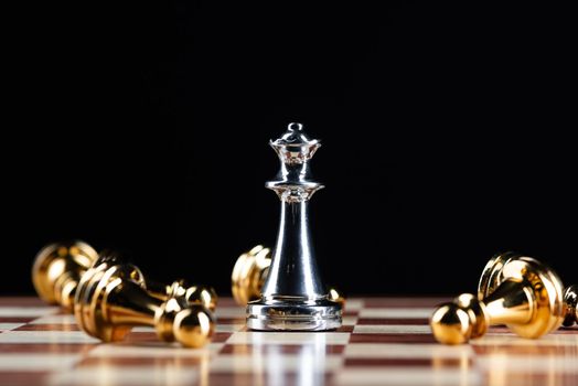 Silver queen chess defeats gold pawns on wooden chessboard. Intellectual duel and tactical battle in business. Strategy planning, leadership and teamwork. Checkmate and winning in game concept.