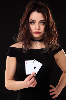 Young woman holding playing cards against a black background. Gambling. Poker. Two Aces.