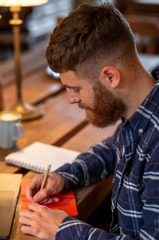 Casual business man or freelancer planning his work on notebook, working on laptop computer with smart phone, cup of coffee on table at coffee shop or home office, working from cafe concept