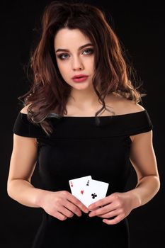 Young woman holding playing cards against a black background. Gambling. Poker. Two Aces.