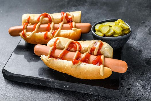 Hot Dog with Yellow Mustard and red ketchup. Black background. Top view.