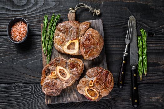 Osso buco cooked Veal shank steak, italian ossobuco. Black wooden background. Top view.
