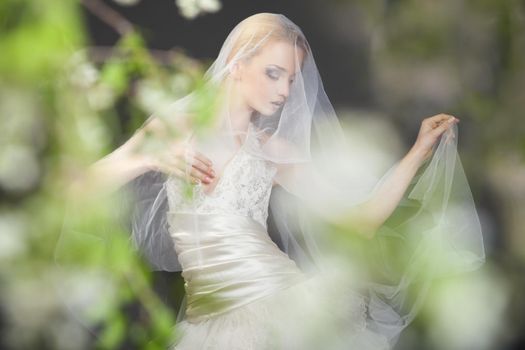 Close up of dreamy beautiful blonde bride walking alone in the park enjoying wind wave and dance