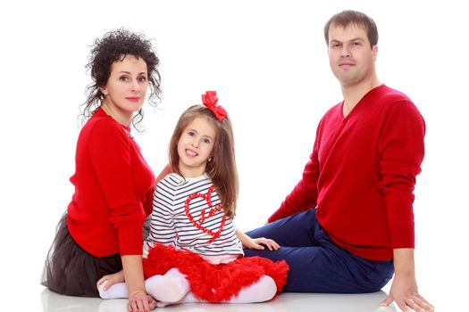 Happy young family dad mom and a little girl in bright red outfits . Dad holds daughter on hands.Isolated on white background.