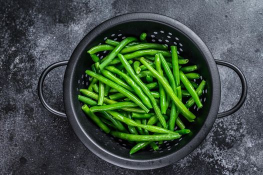 Raw green beans in a colander. Black background. top view.