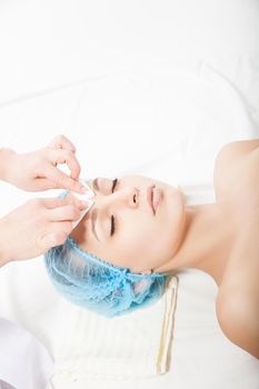 Woman laying at cosmetic procedure made by beautician. Vertical indoors shot