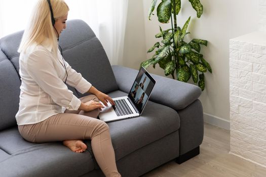 Beautiful smiling female student using online education service. Young woman looking in laptop display watching training course and listening it with headphones. Modern study technology concept