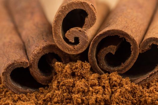 Cinnamon sticks with cinnamon powder on wooden background