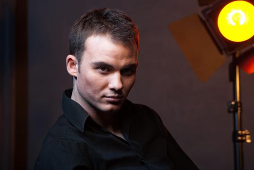 Closeup portrait of a sexy male model in studio on dark grey background with flashes